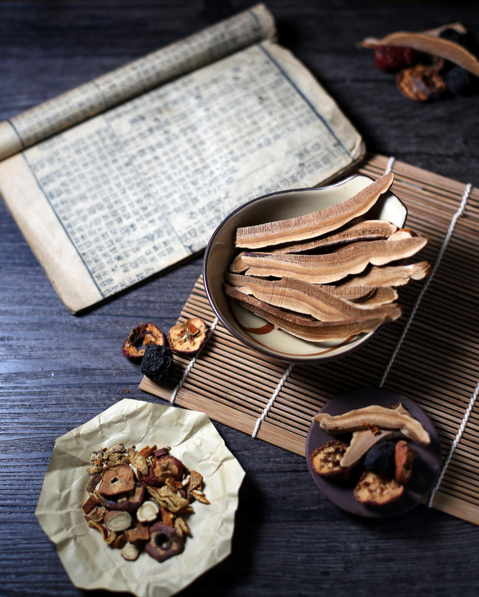 raw Chinese herbs in a dispensary bown and classical Chinese text